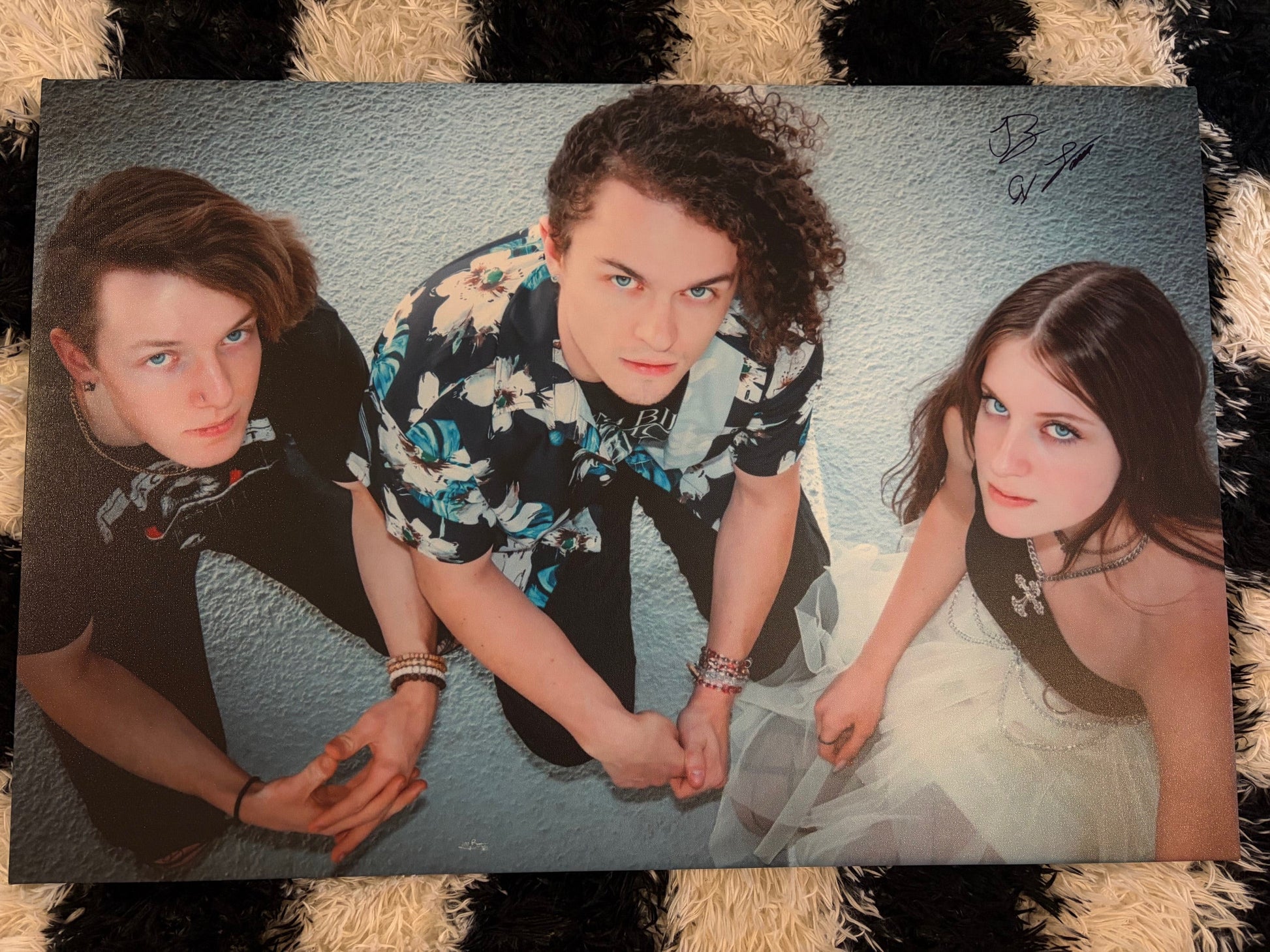 Three people lying on a textured surface with a checkered border